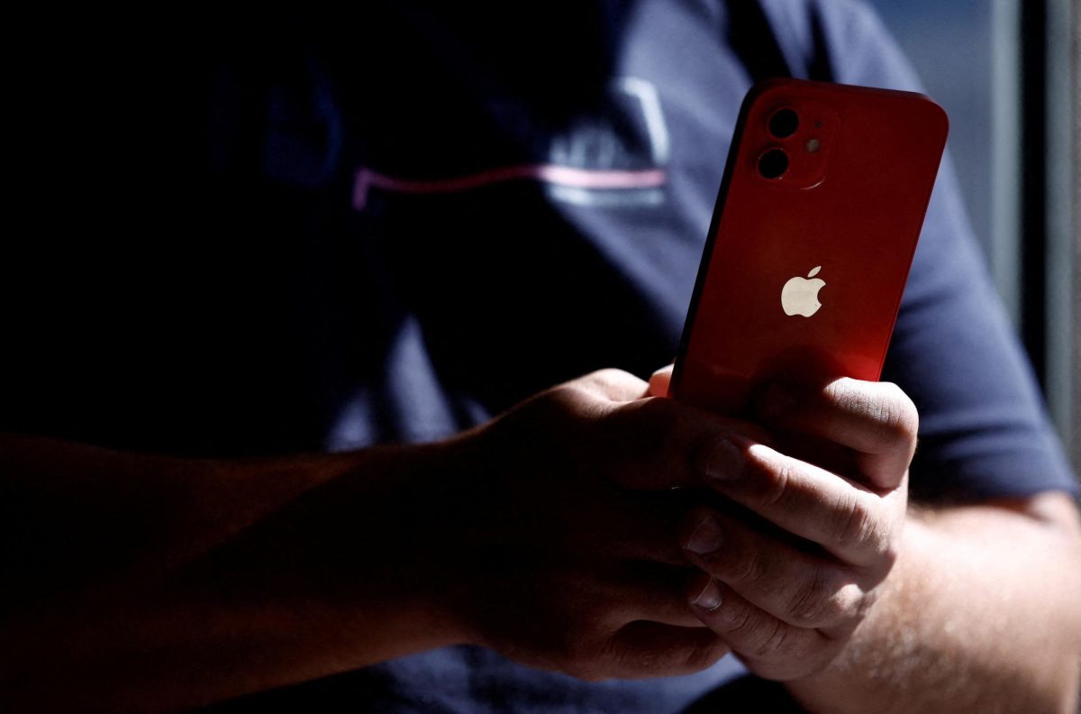 A man poses with an Apple iPhone 12 in a mobile phone store in Nantes, France, September 13, 2023. REUTERS/Stephane Mahe/File photo