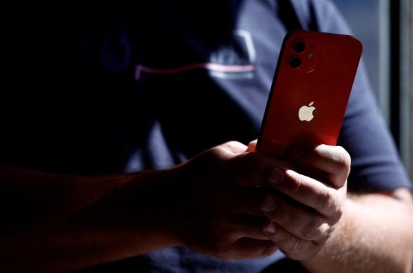 A man poses with an Apple iPhone 12 in a mobile phone store in Nantes, France, September 13, 2023. REUTERS/Stephane Mahe/File photo